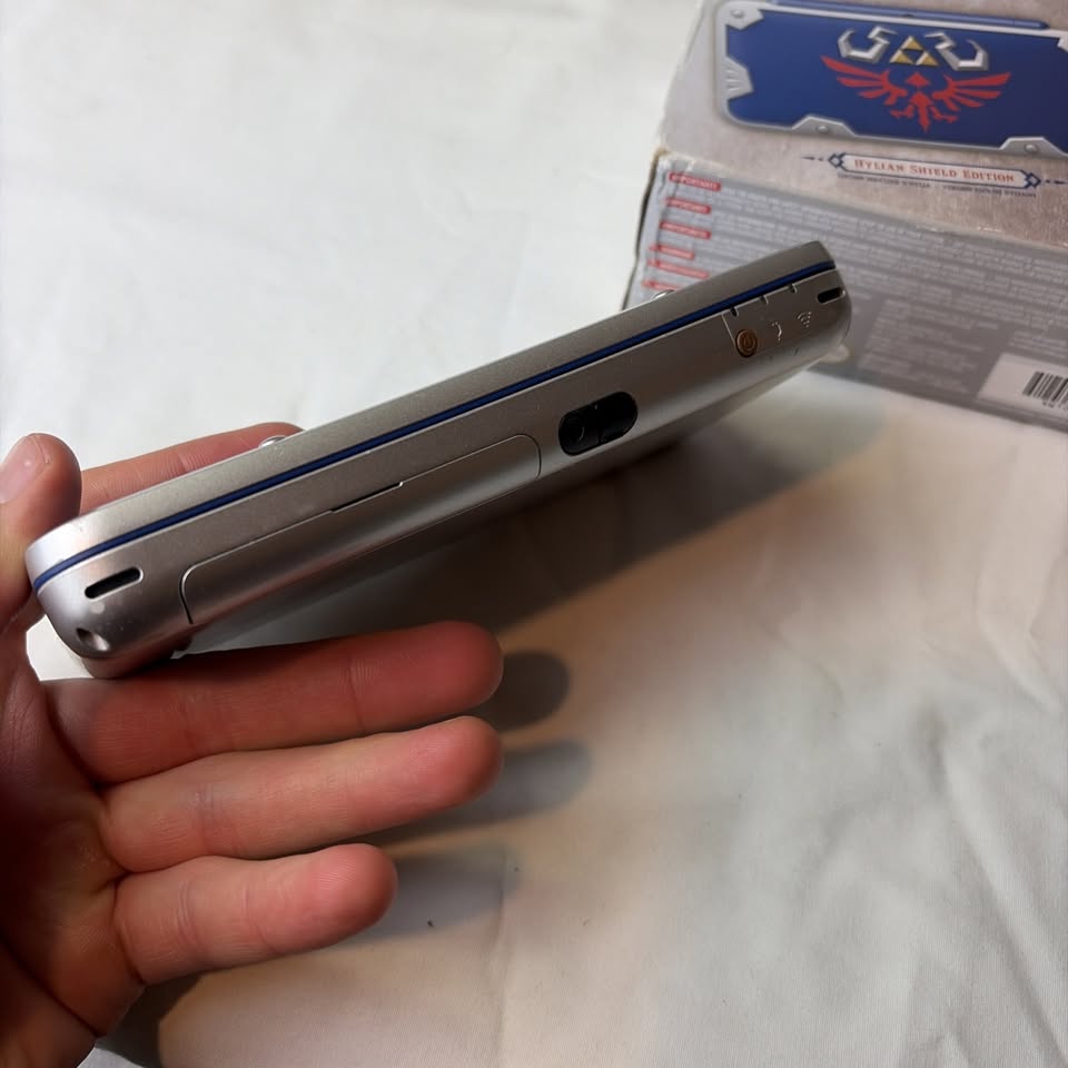 Light Gray Nintendo New 2DS XL Hylian Shield Edition + Cargador Original – Edición Especial Zelda