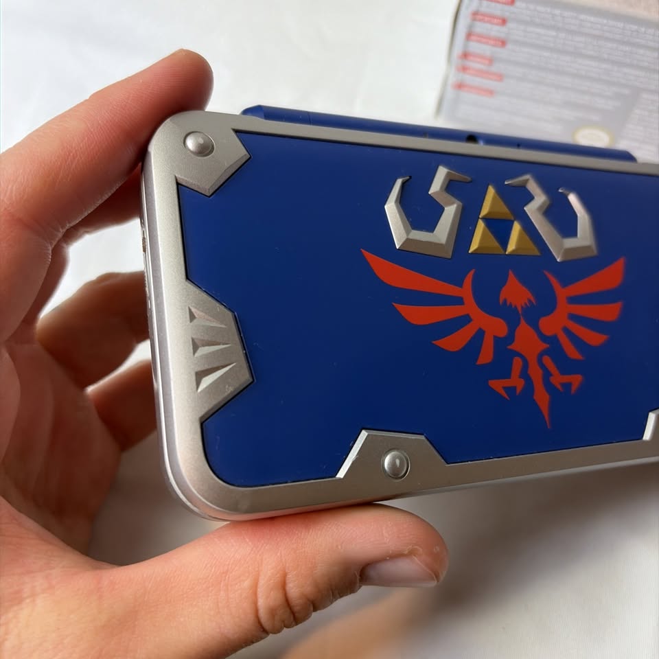 Lavender Nintendo New 2DS XL Hylian Shield Edition + Cargador Original – Edición Especial Zelda