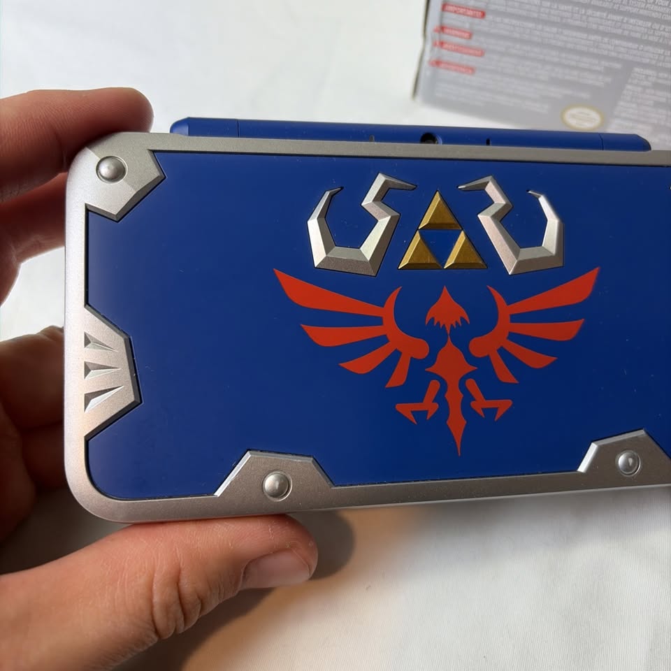 Light Gray Nintendo New 2DS XL Hylian Shield Edition + Cargador Original – Edición Especial Zelda