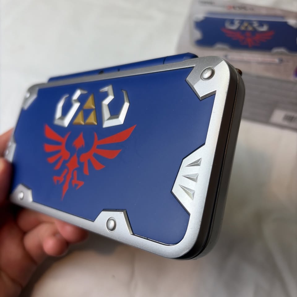Light Gray Nintendo New 2DS XL Hylian Shield Edition + Cargador Original – Edición Especial Zelda