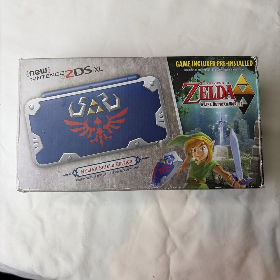Light Gray Nintendo New 2DS XL Hylian Shield Edition + Cargador Original – Edición Especial Zelda